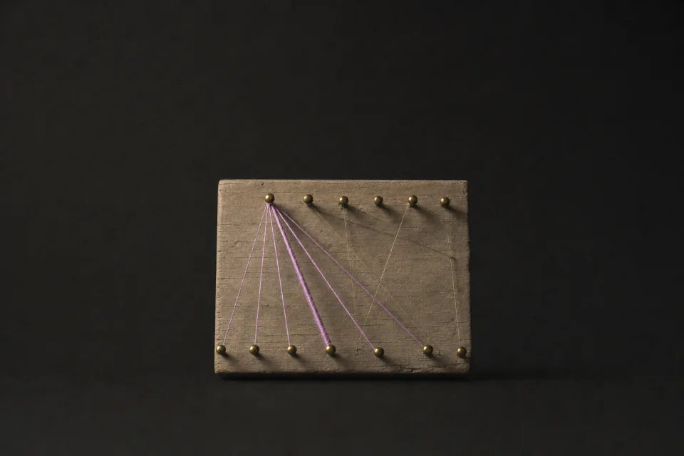 A pin board where threads of different thickness run from one pin to every pin in the row below