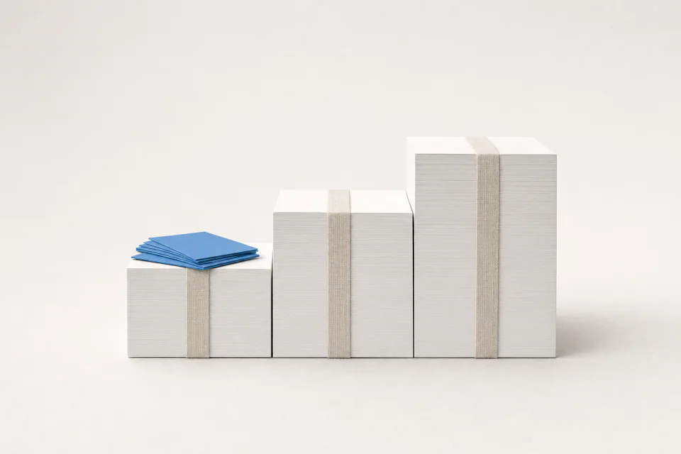 Three squared paper stacks stepping up in size, a small loose pile of cards on the smallest