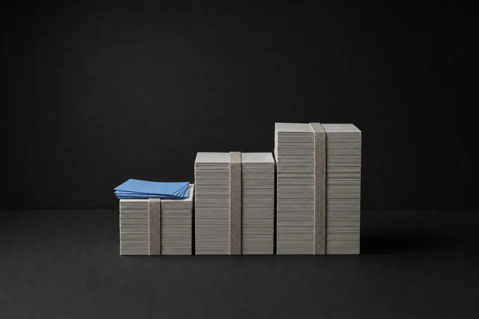Three squared paper stacks stepping up in size, a small loose pile of cards on the smallest