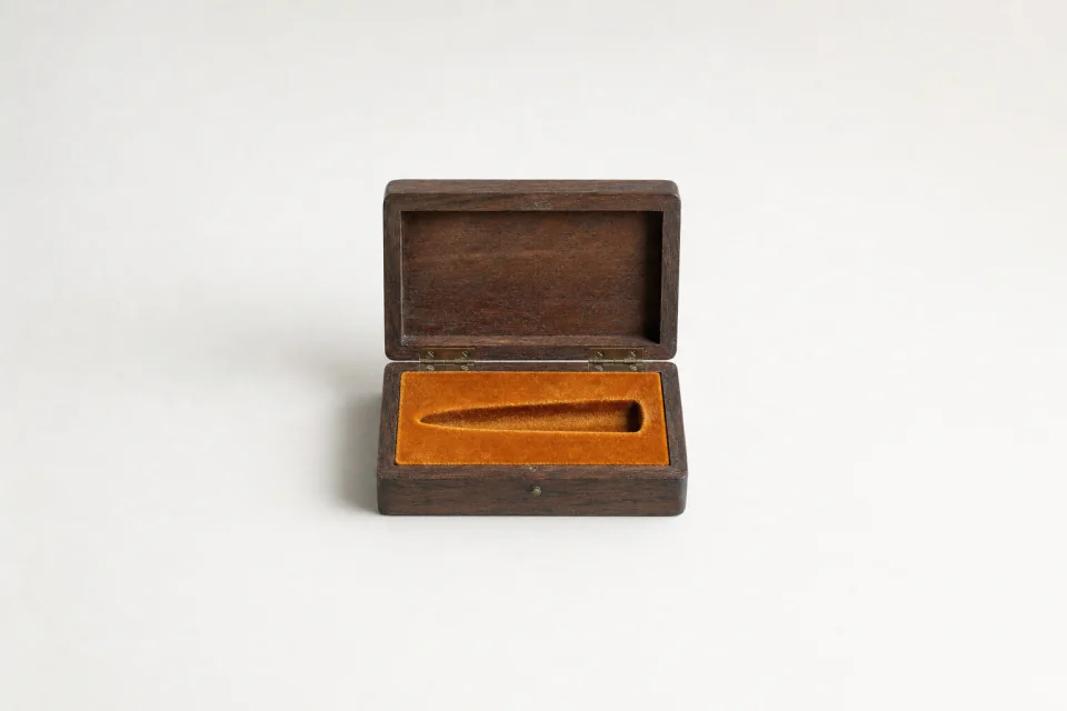 An open walnut case whose velvet lining is moulded for a single bullet, and the recess is empty