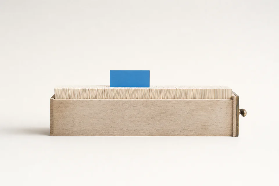 A card catalogue drawer packed with blank index cards, one card lifted above the rest