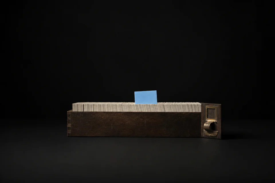 A card catalogue drawer packed with blank index cards, one card lifted above the rest
